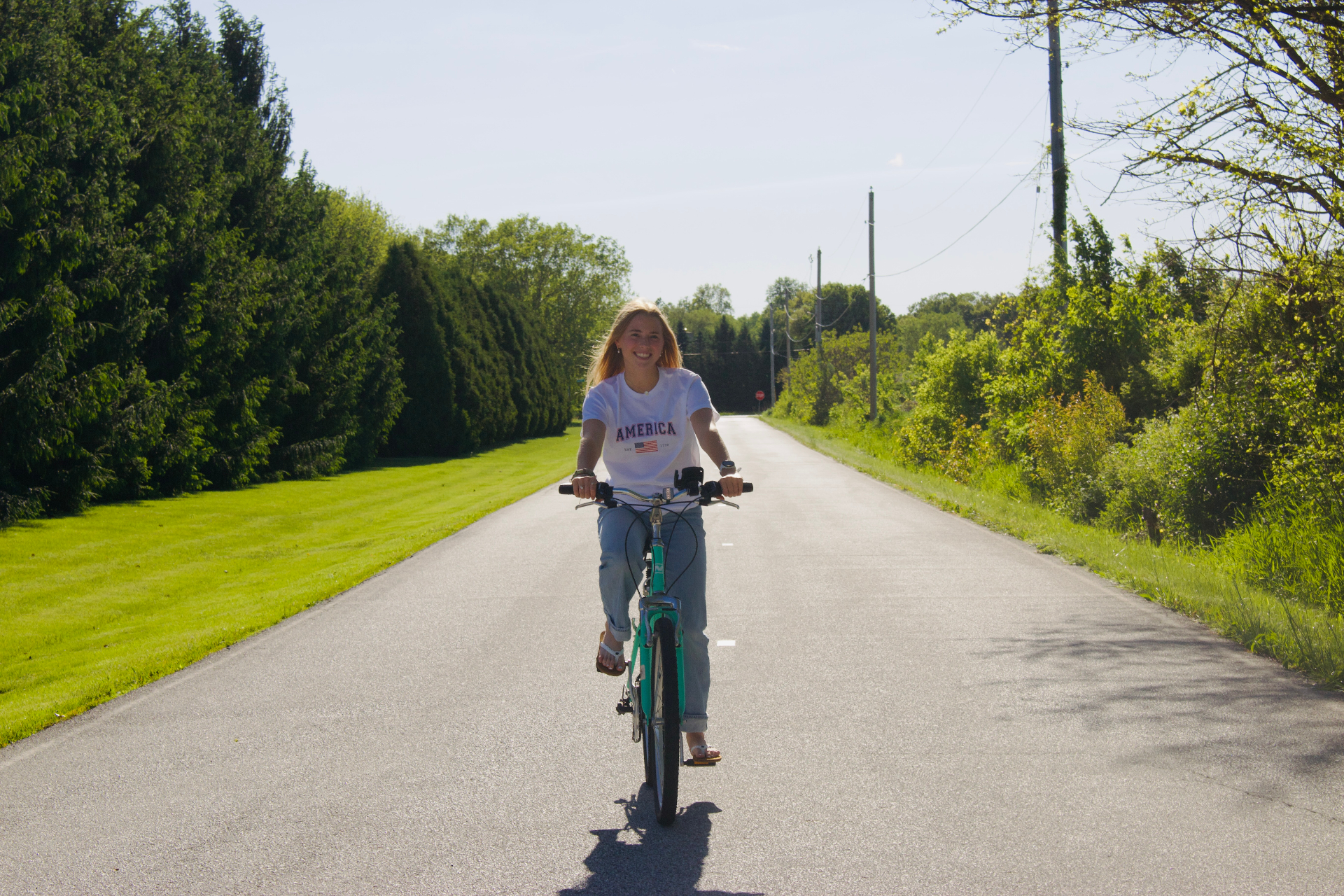 Summer bike ride down a Midwest country road in an America tee